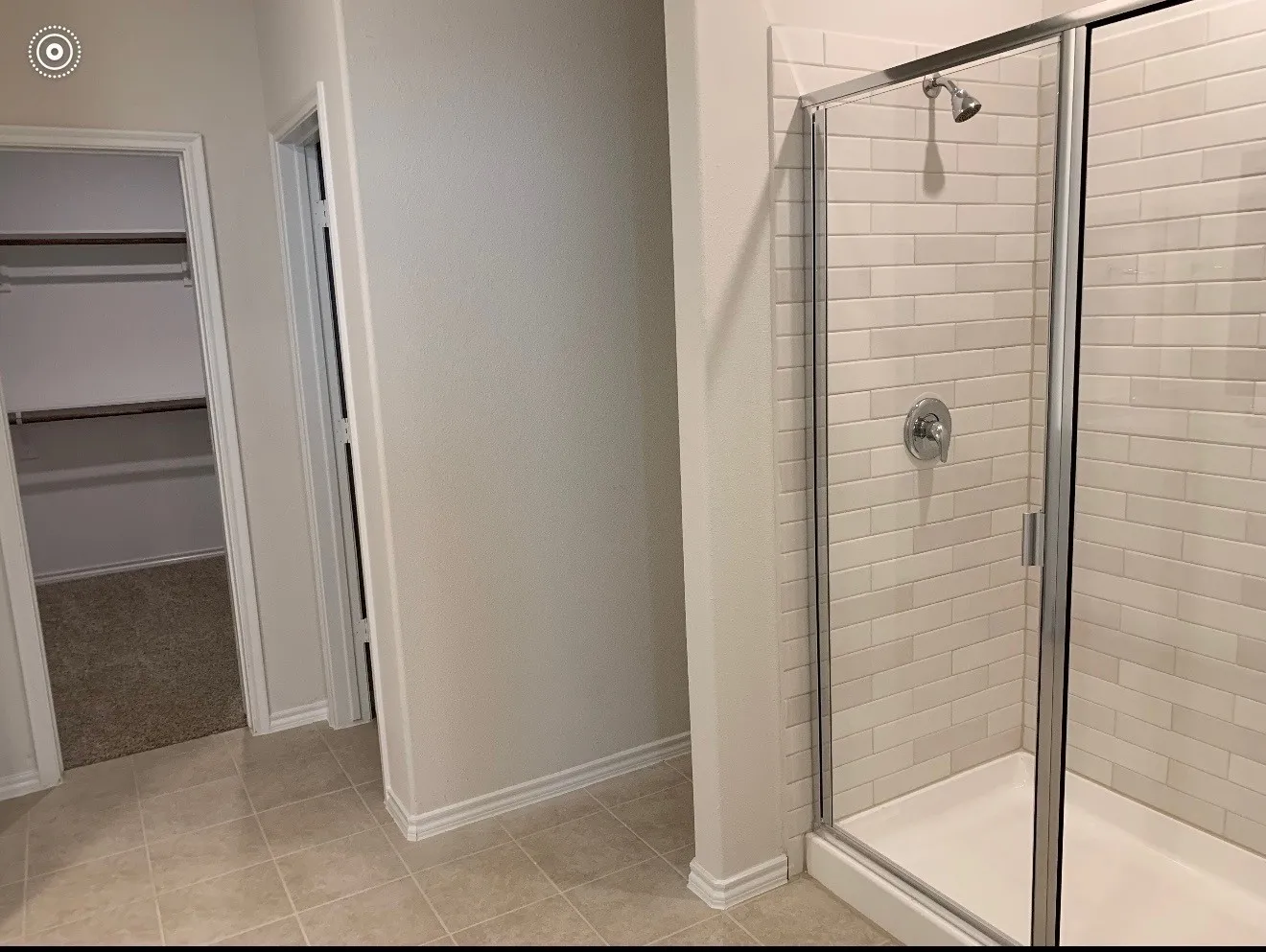 Tiled flooring, subway tile shower surround, glass-enclosed shower, chrome shower fixtures, and a walk-in closet with shelving