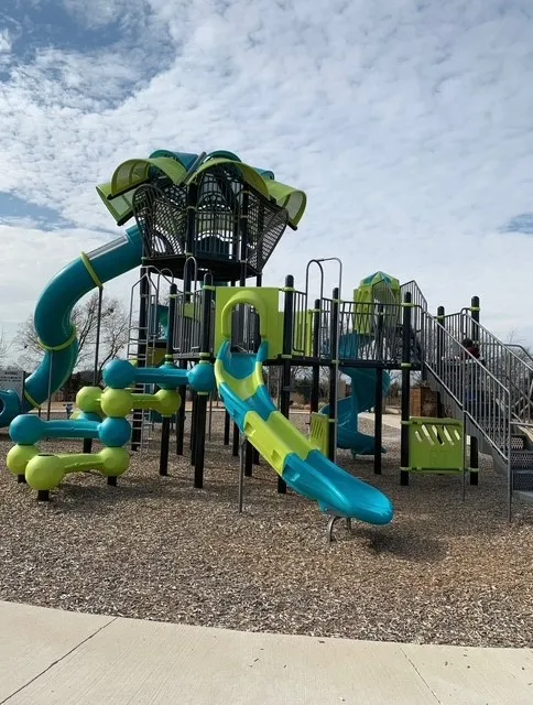 Multi-level play structure with multiple slides, climbing elements, and protective ground covering