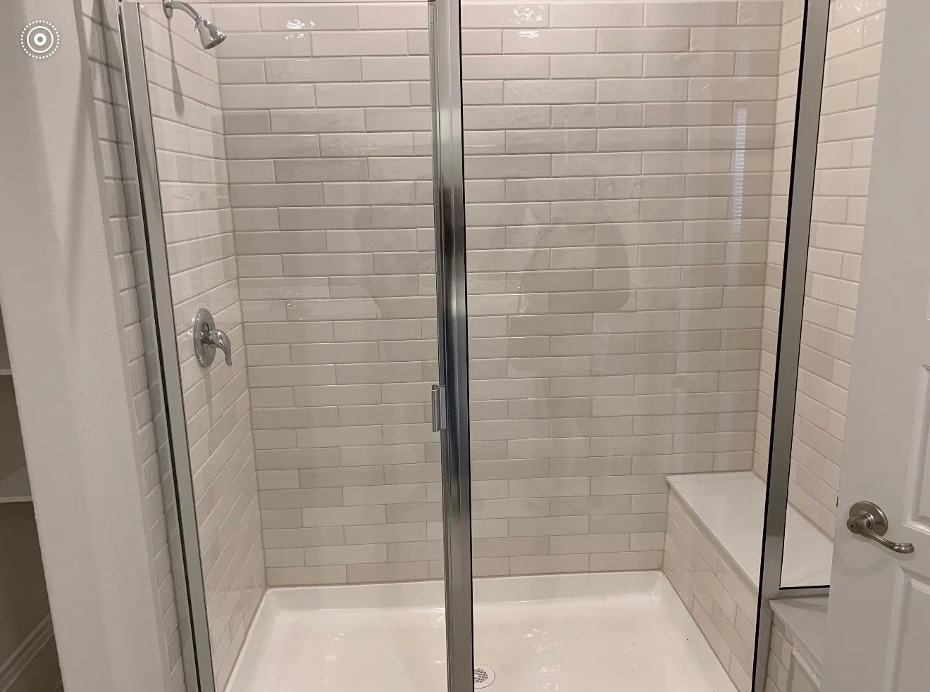 Glass-enclosed shower with subway tile surround, built-in bench, and chrome fixtures