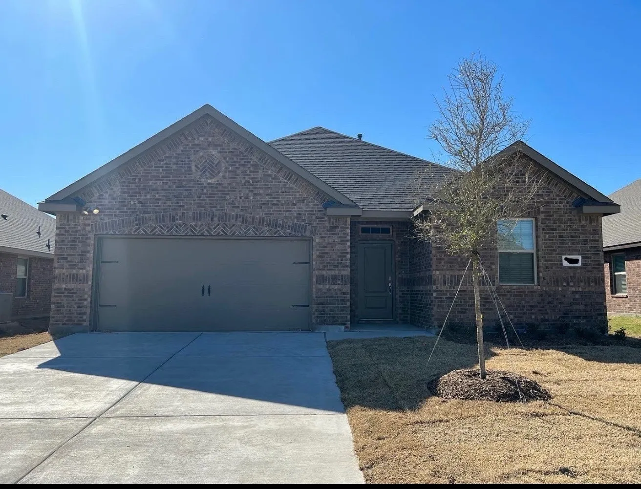Brick exterior with decorative brickwork, asphalt shingle roof, attached garage, and concrete driveway