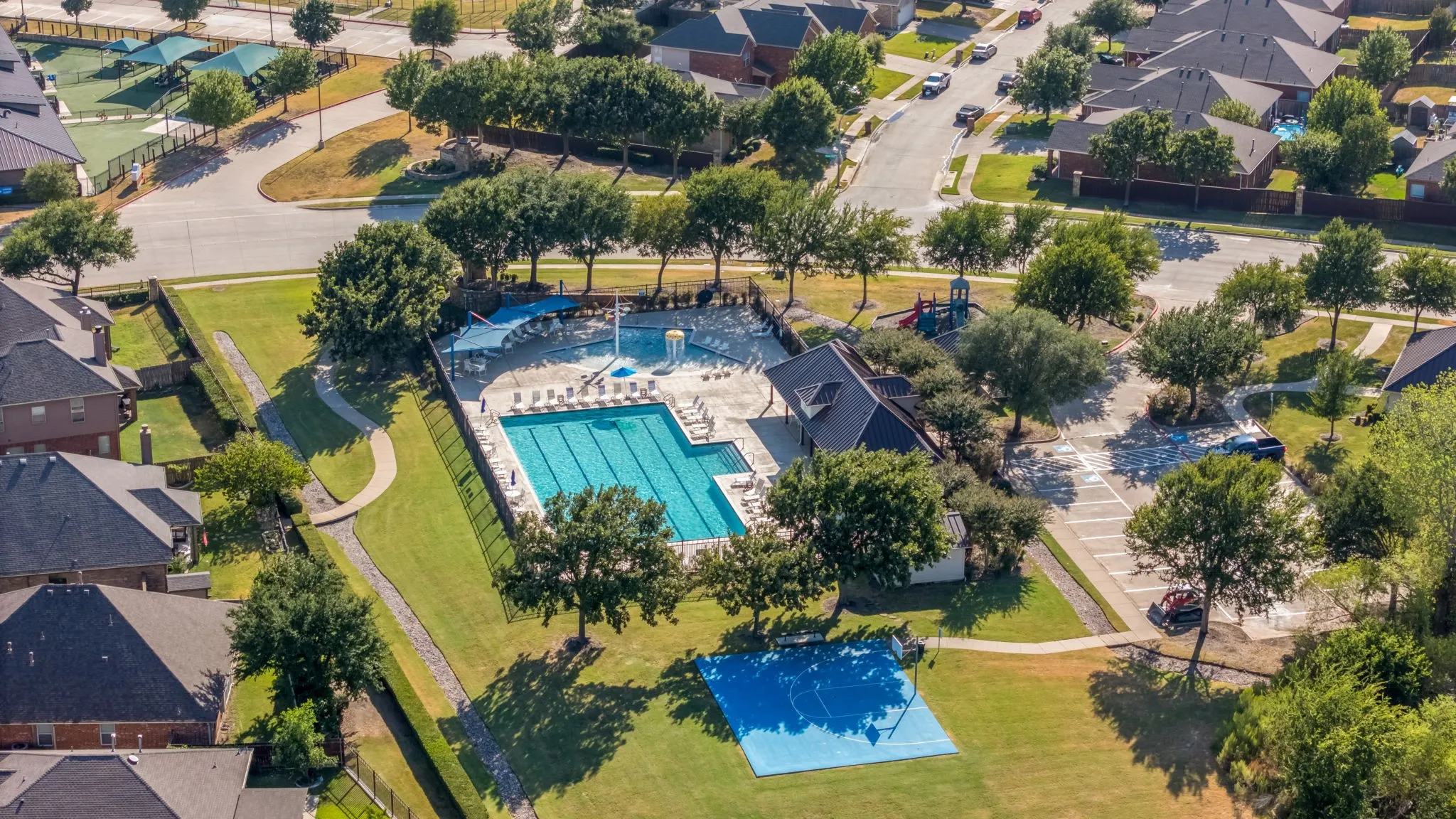 Community amenities featuring a swimming pool, shaded seating areas, amenity center, hardscaped paths, and a basketball court