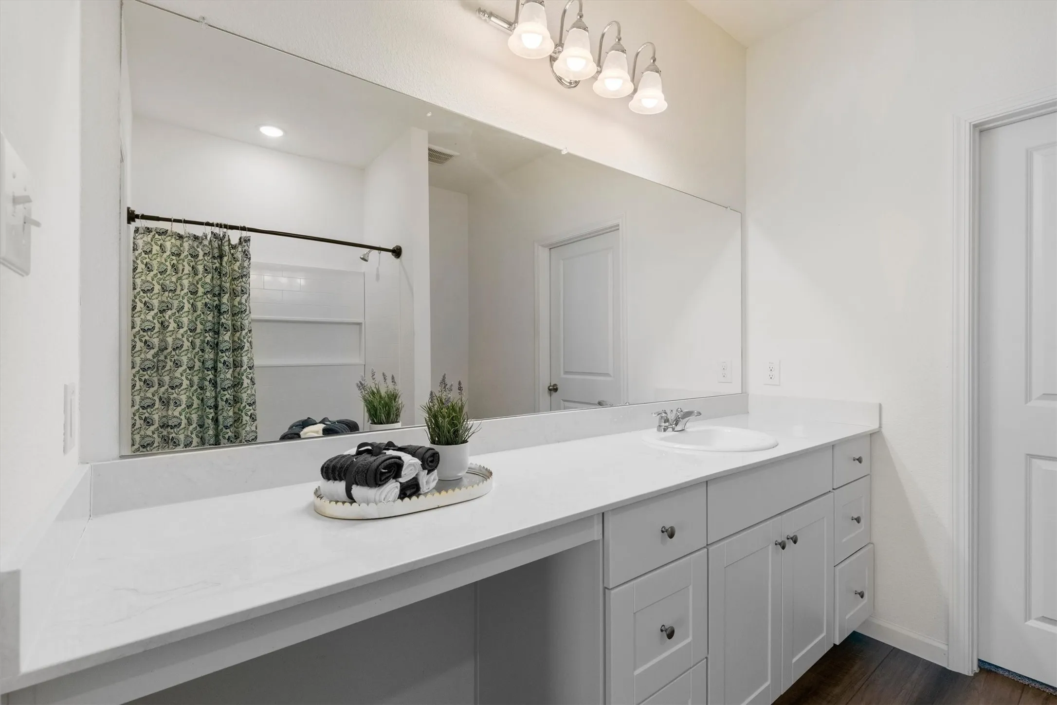 Expansive vanity with white countertops, undermount sink, and ample storage cabinetry