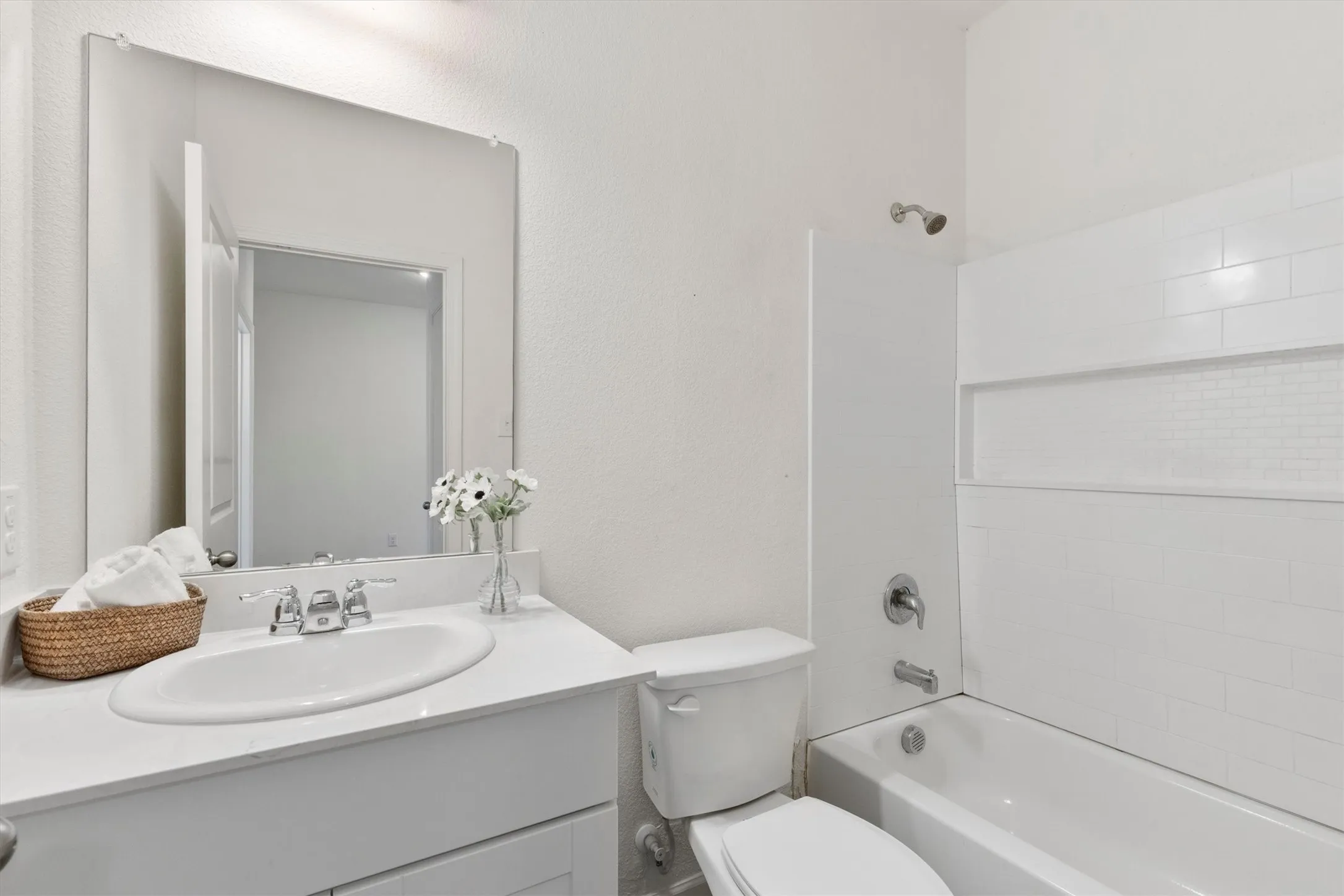White vanity with an integrated sink, polished chrome faucet, and large wall-mounted mirror