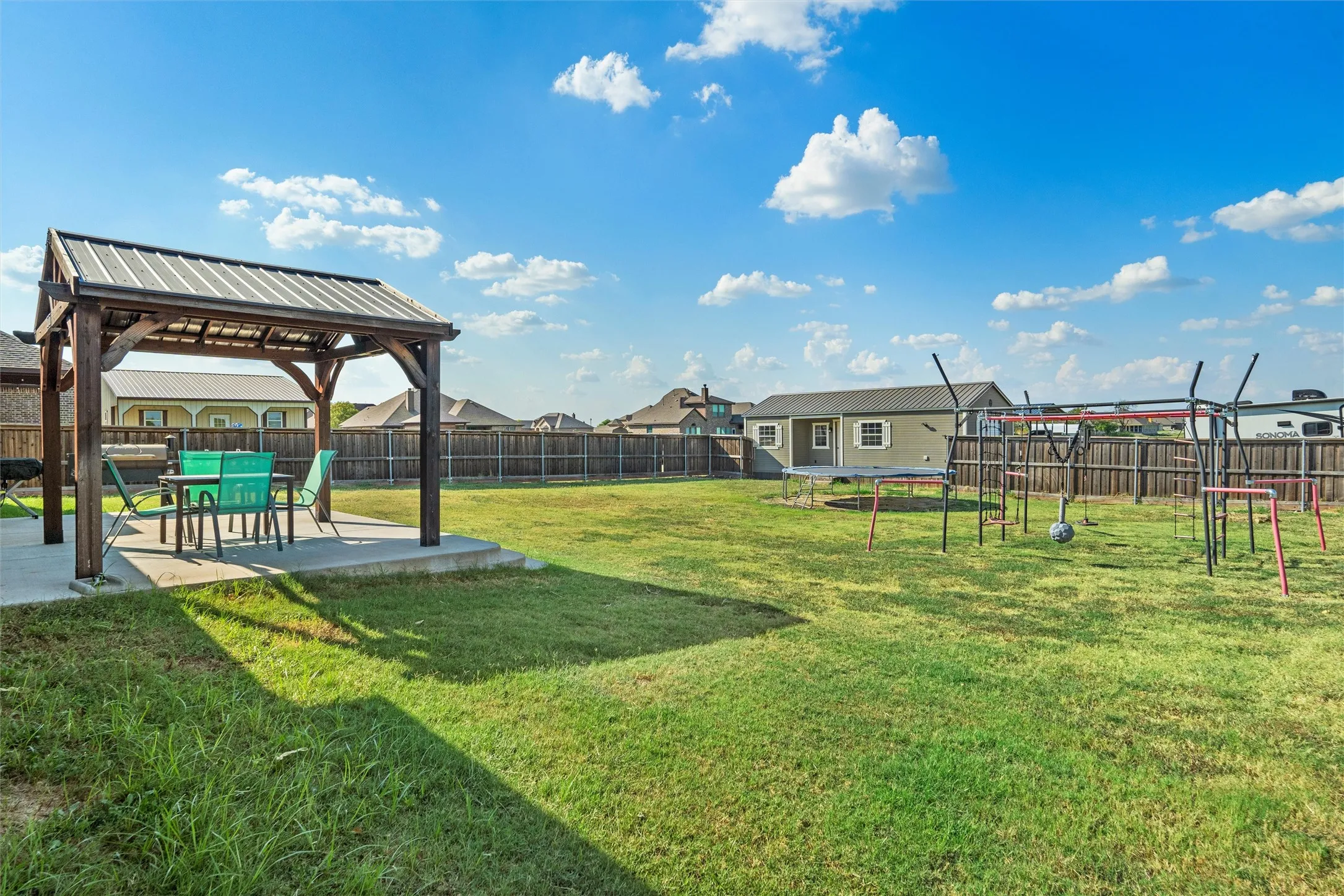 Expansive backyard featuring a covered patio, a separate structure, and a wood privacy fence