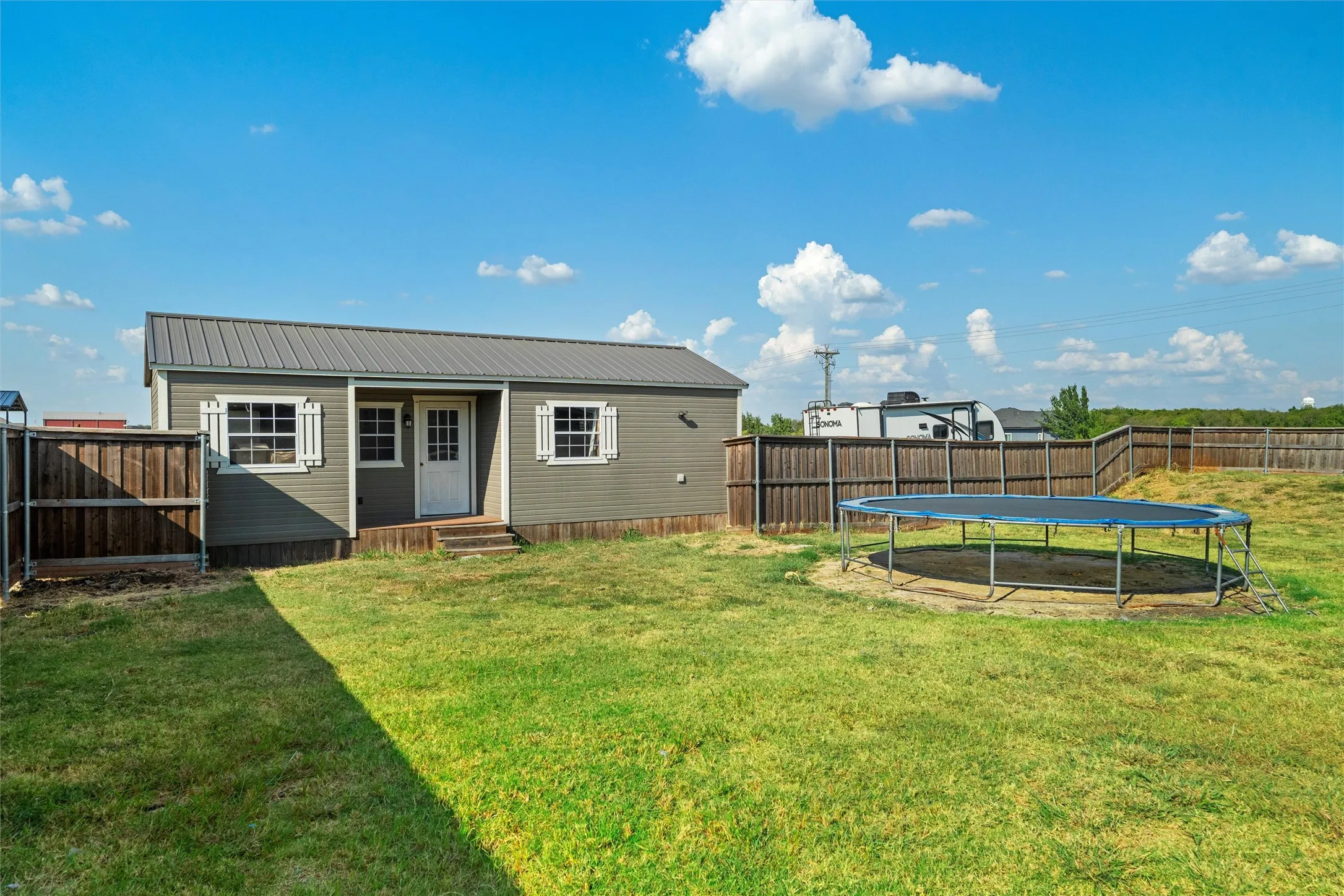 Detached outbuilding with a metal roof, wood siding, and white window shutters