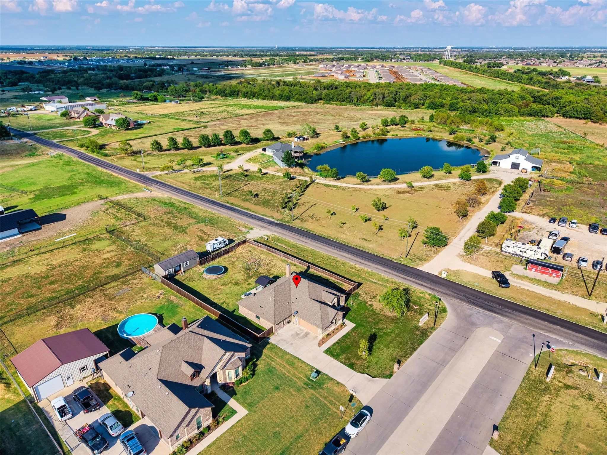 Expansive property featuring a paved road, a serene pond, and open green spaces