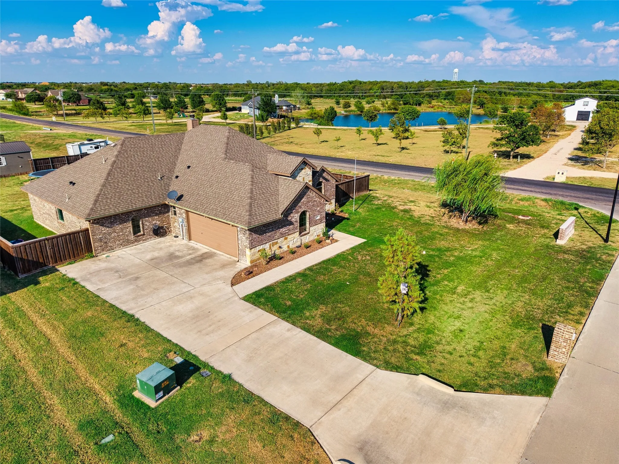 Brick exterior with an attached garage, paved driveway, and established landscaping