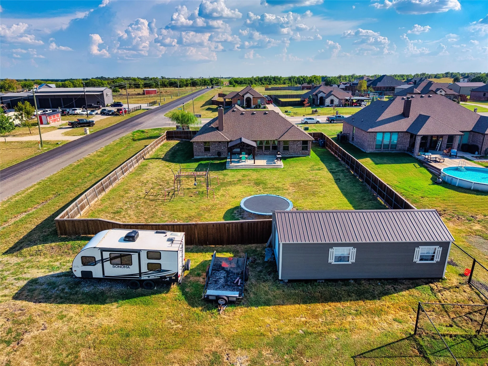Expansive property featuring a separate outbuilding, a fenced backyard, and a paved road frontage
