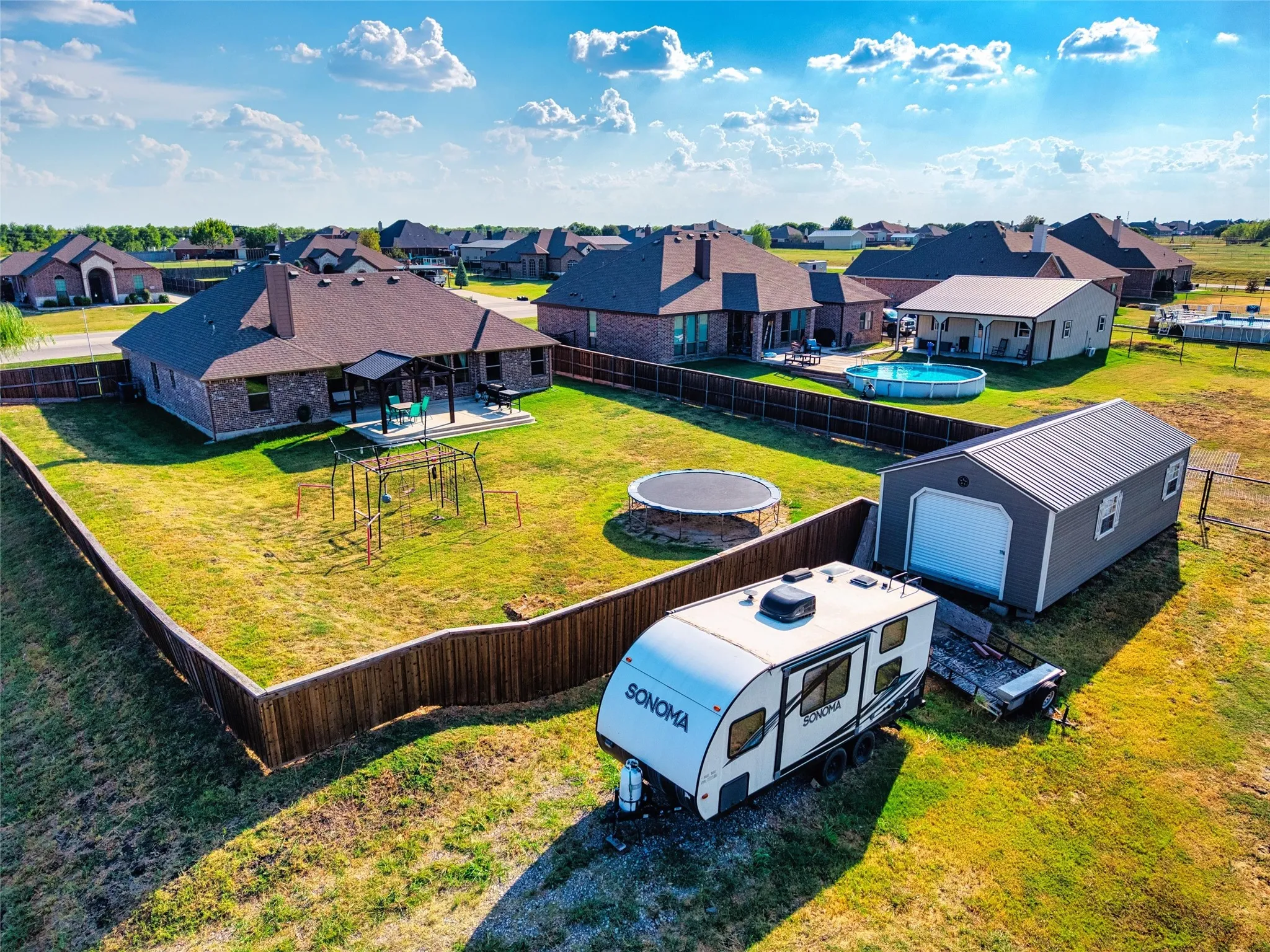 Expansive fenced yard featuring a storage shed, an above-ground pool, and a trampoline