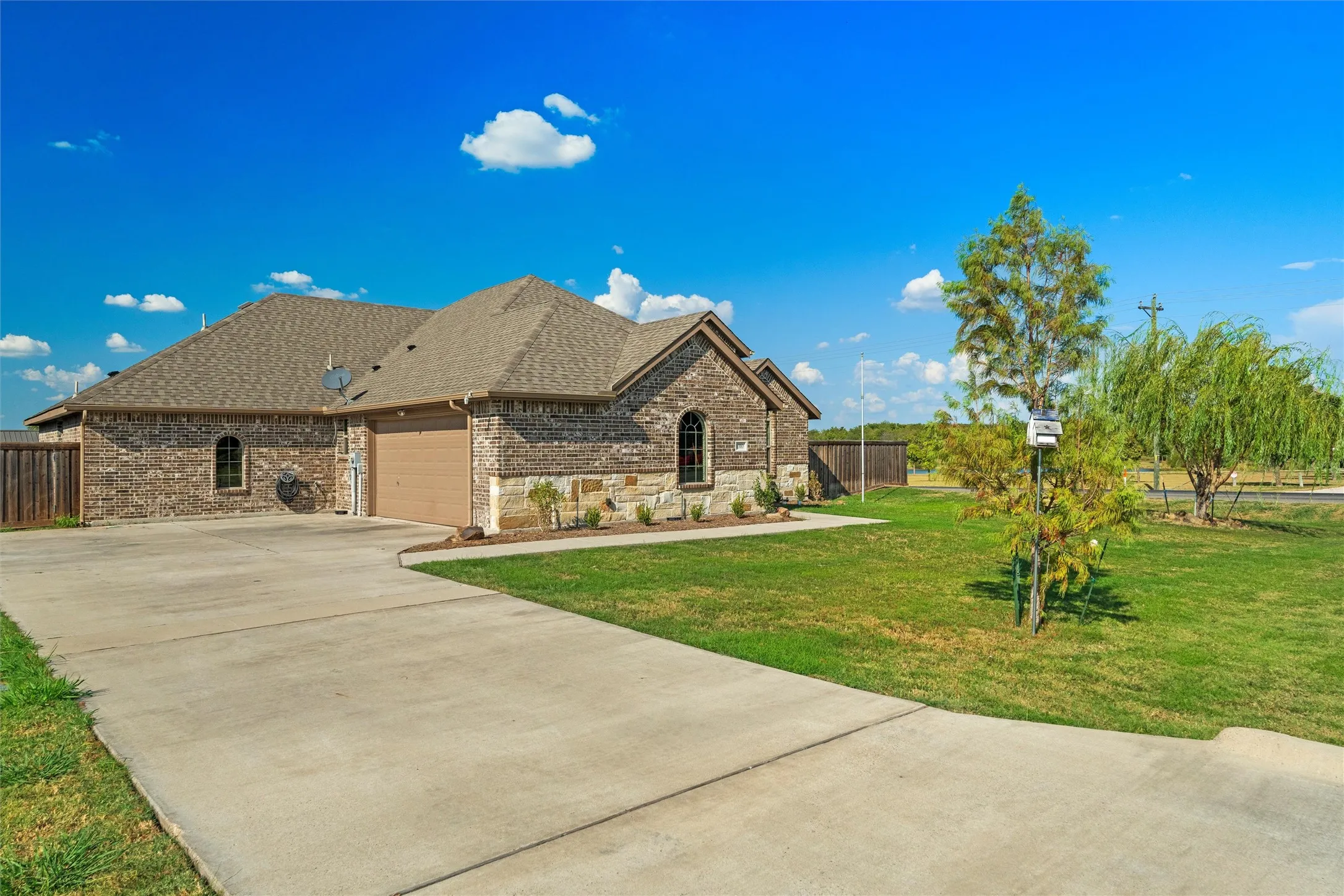 Brick and stone exterior with arched window accents, attached garage, and concrete driveway