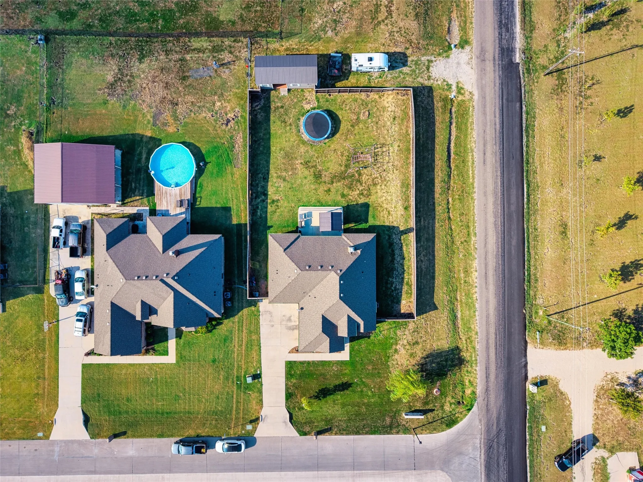 Aerial view showcasing two residential properties, each featuring a private driveway, pitched roofline, and established grassy areas