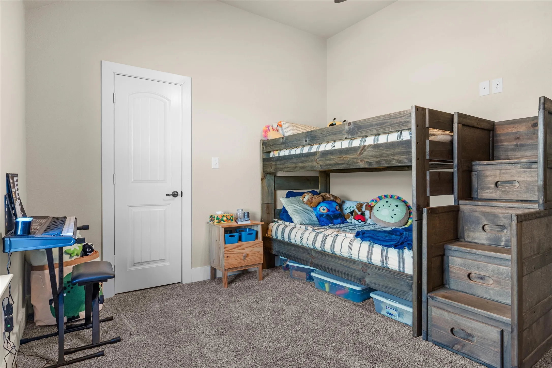Neutral tone wall paint, textured carpeting, white interior door with dark hardware, and a ceiling fan