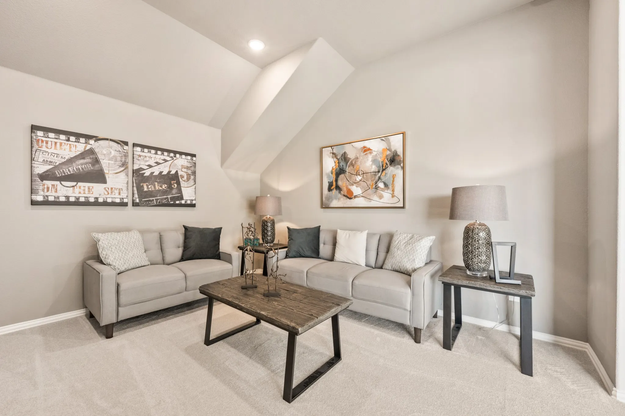 Sloped ceiling design, recessed lighting, and soft neutral wall tones