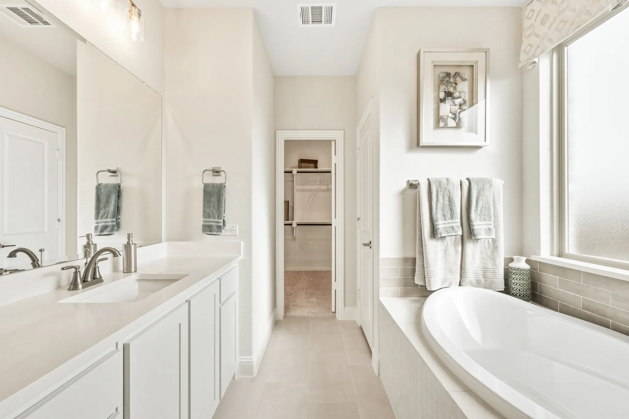 Vanity with dual sinks, brushed nickel fixtures, and white cabinetry