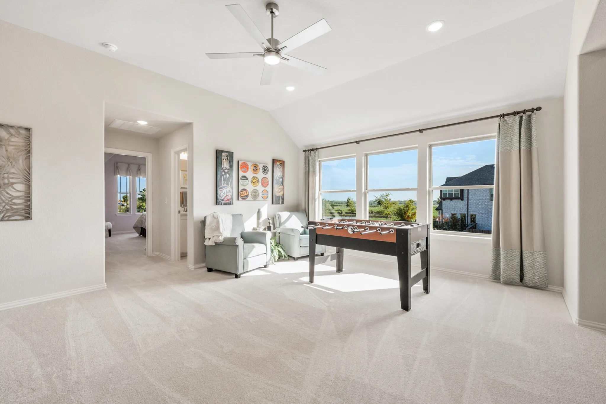 Spacious room with sloped ceiling, recessed lighting, and a ceiling fan with integrated light