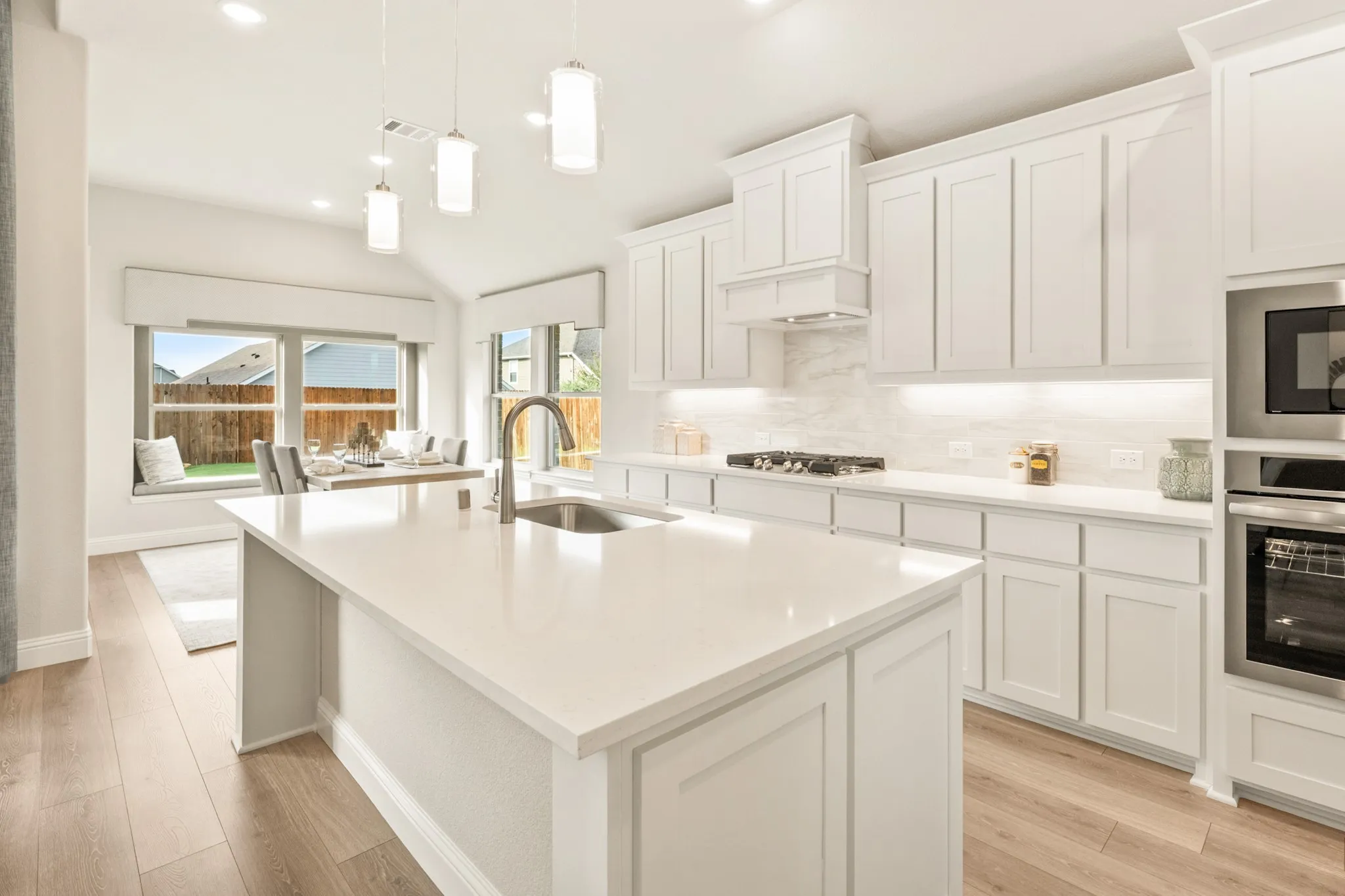 Kitchen featuring a large island with an undermount sink, white cabinetry with undermount lighting, and stainless steel appliances