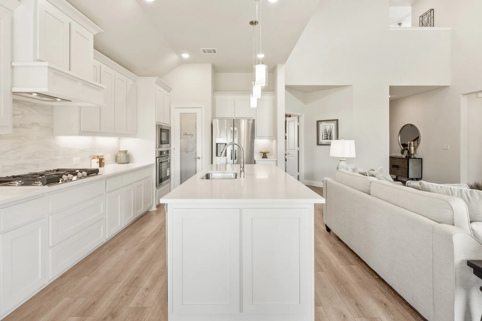Kitchen with white cabinetry, stainless steel appliances, a center island, and wood-finish flooring