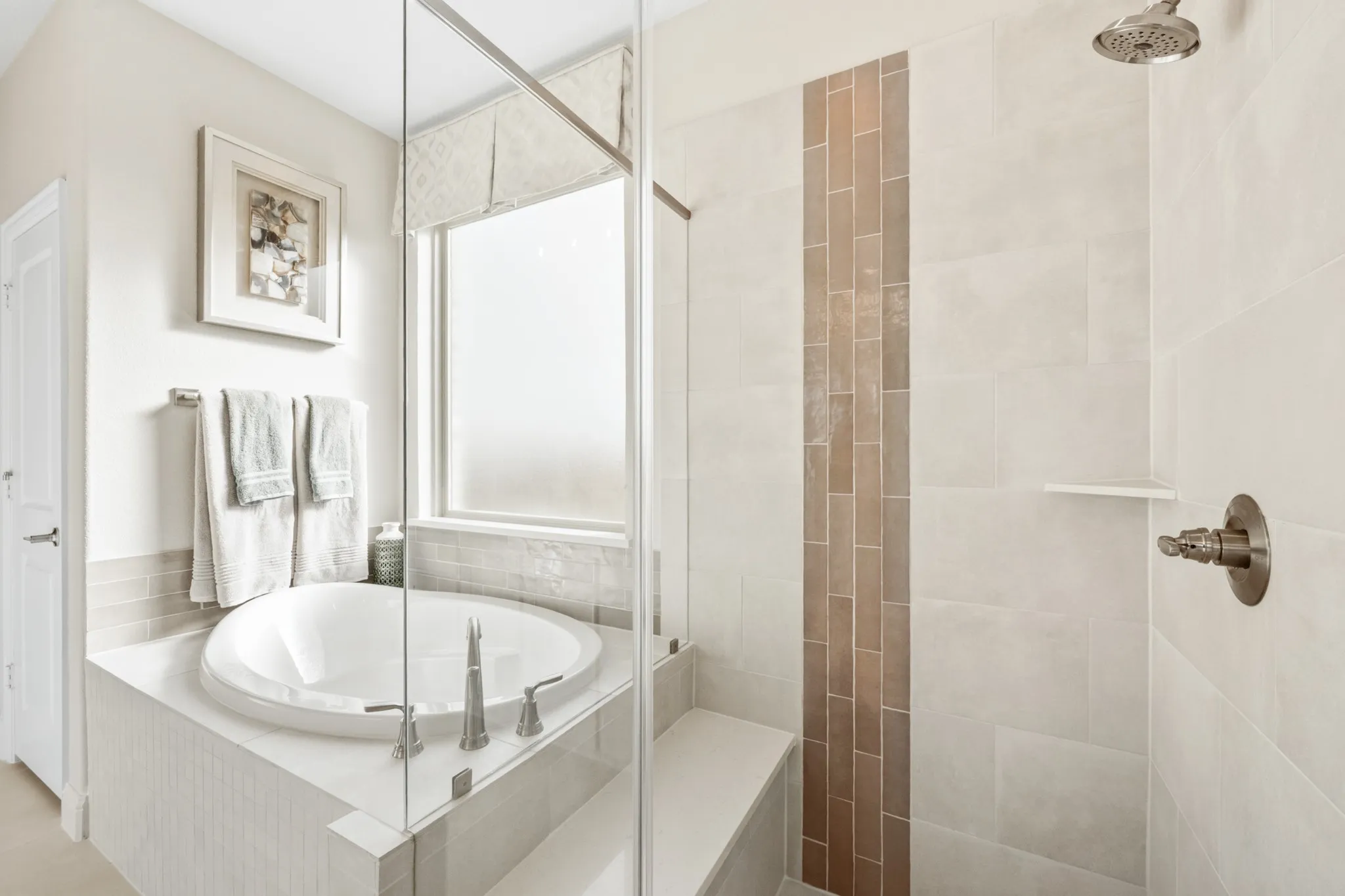 Built-in soaking tub with brushed nickel fixtures, glass-enclosed shower with a built-in bench, and a vertical accent tile strip