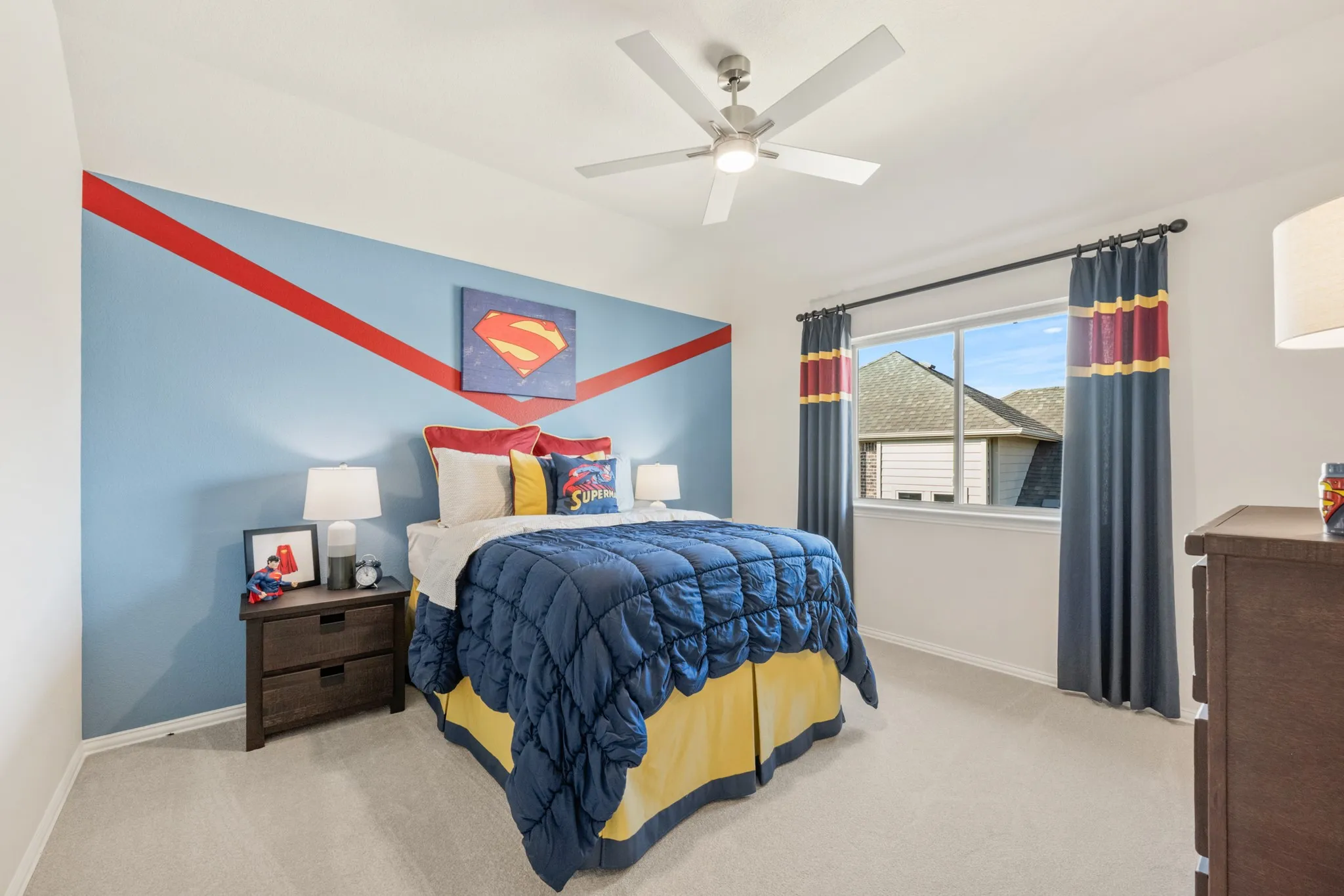 Carpeted bedroom featuring a ceiling fan with integrated lighting, a window with a sill, and a contrasting accent wall