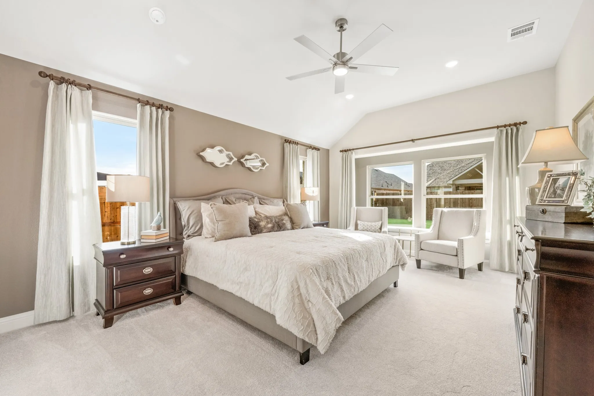 Vaulted ceiling with a ceiling fan, recessed lighting, carpet flooring, large windows, and dark wood-finish cabinetry