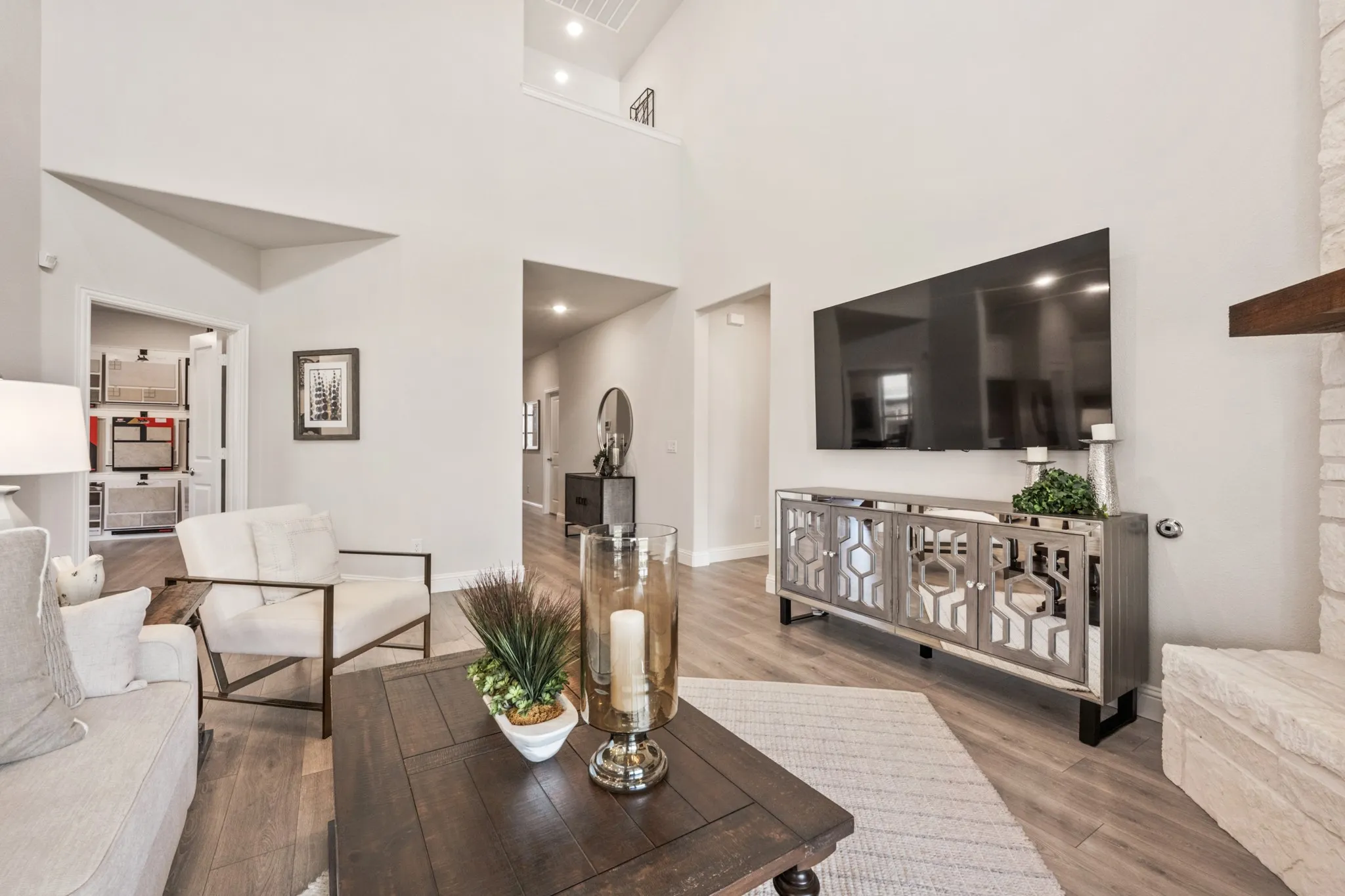 Vaulted ceilings with recessed lighting, wood-finish flooring, and a stone-clad hearth