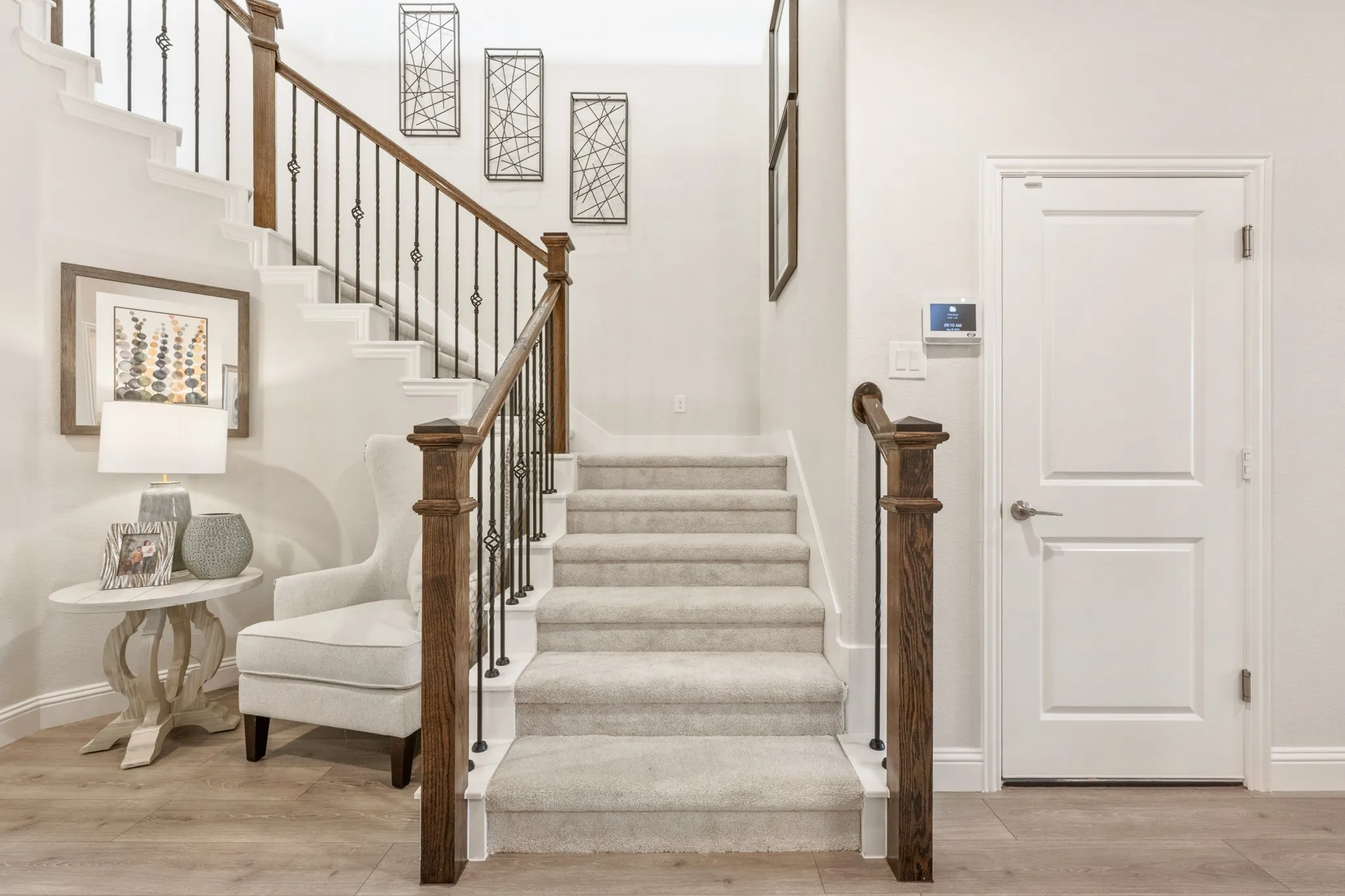 Staircase featuring wood-finish handrail, wrought iron balusters, and carpeted treads