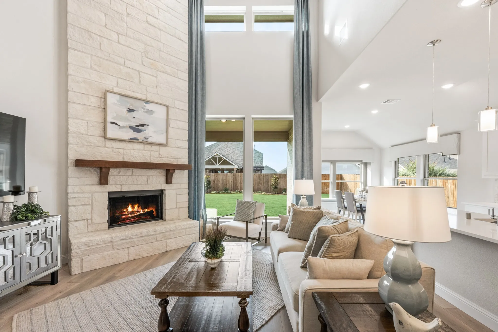 Two-story stone fireplace with wood mantel, vaulted ceilings, and wood-finish flooring