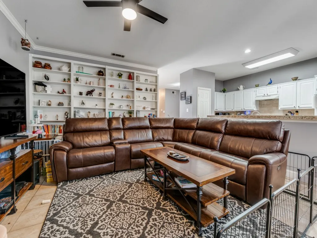 Built-in shelving, ceiling fan, recessed lighting, white cabinetry, and a kitchen pass-through with a breakfast bar