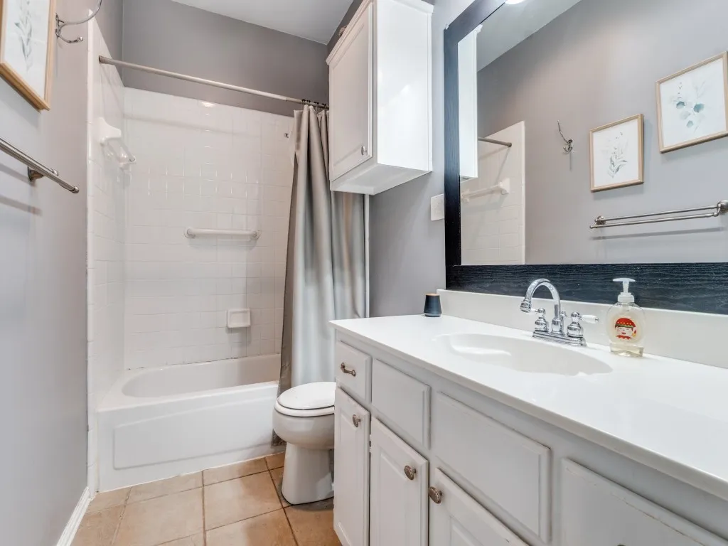 Bathroom featuring a full-size tub with white subway tile surround, white vanity with integrated sink, chrome fixtures, and neutral tile flooring