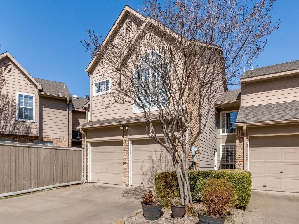Two-story exterior with siding and brick accents, featuring a two-car garage and a paved driveway