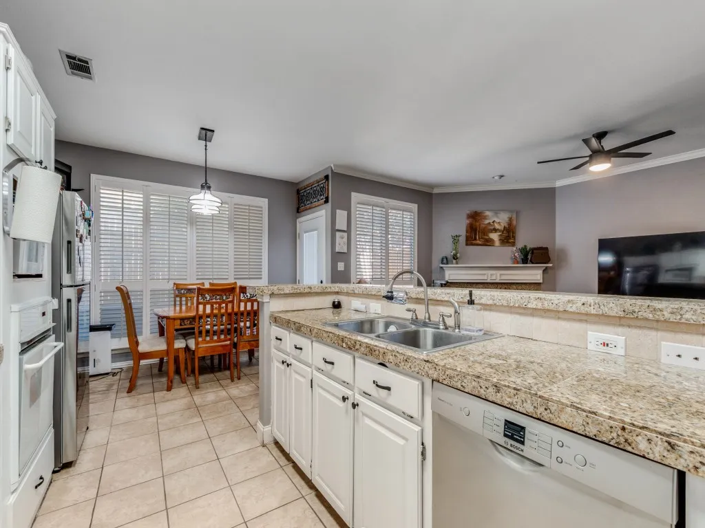 Kitchen featuring a double basin stainless steel sink, white cabinetry, and light-toned tile flooring