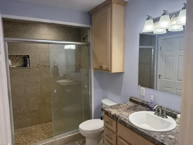 Barndominium - Shower with glass enclosure, tiled walls, pebble-finish flooring, and built-in niche.