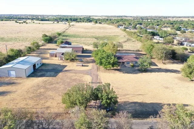 Expansive property - 13.76 acres- featuring a single-story residence, multiple outbuildings, and a gravel driveway
