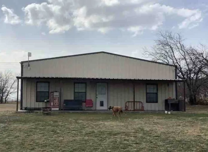 Barndominium is metal-sided structure with a sloped metal roof, covered front porch, and multiple windows.