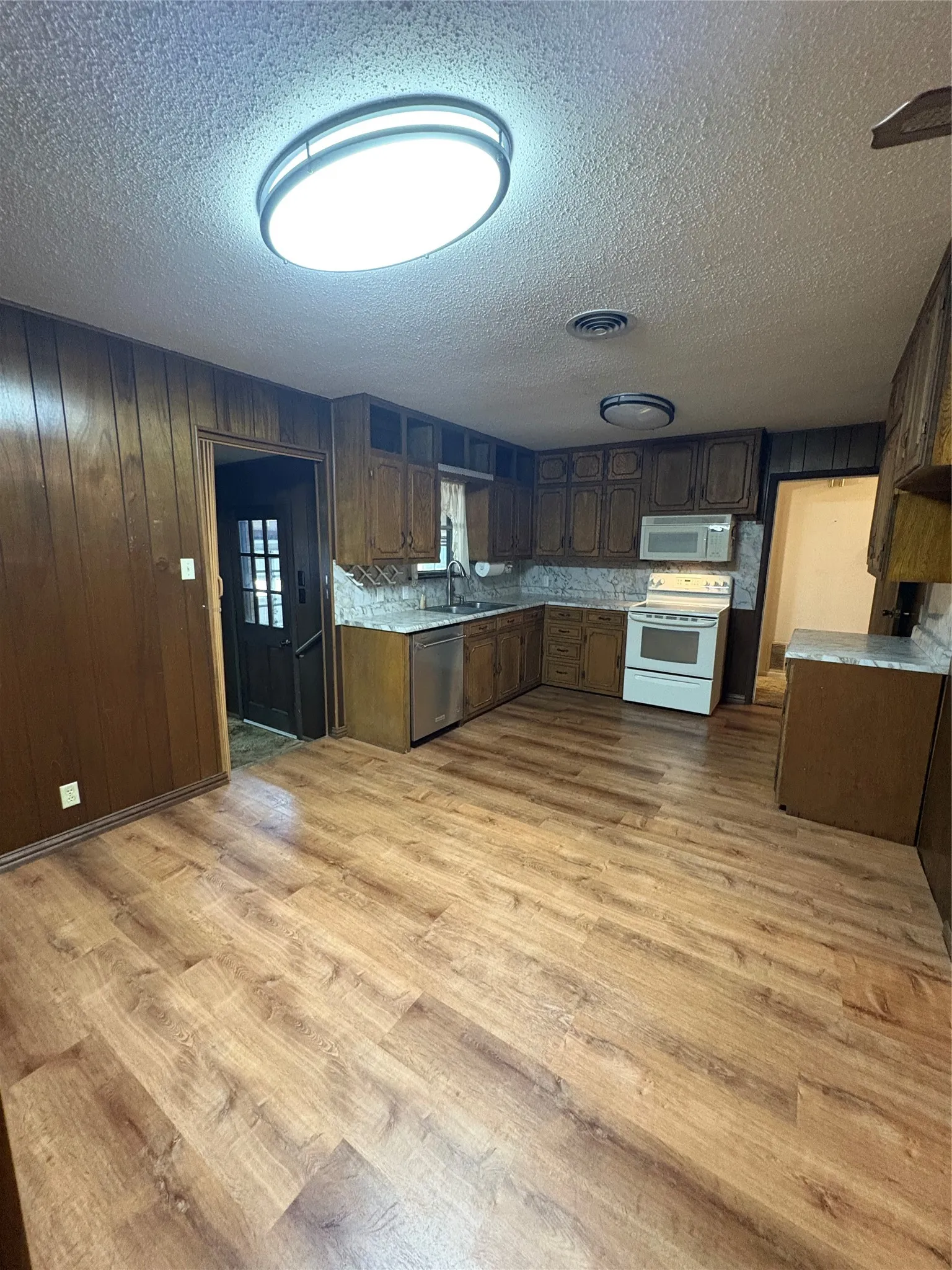 Wood-finish flooring, built-in cabinetry, stainless steel dishwasher, white range, and recessed lighting fixtures