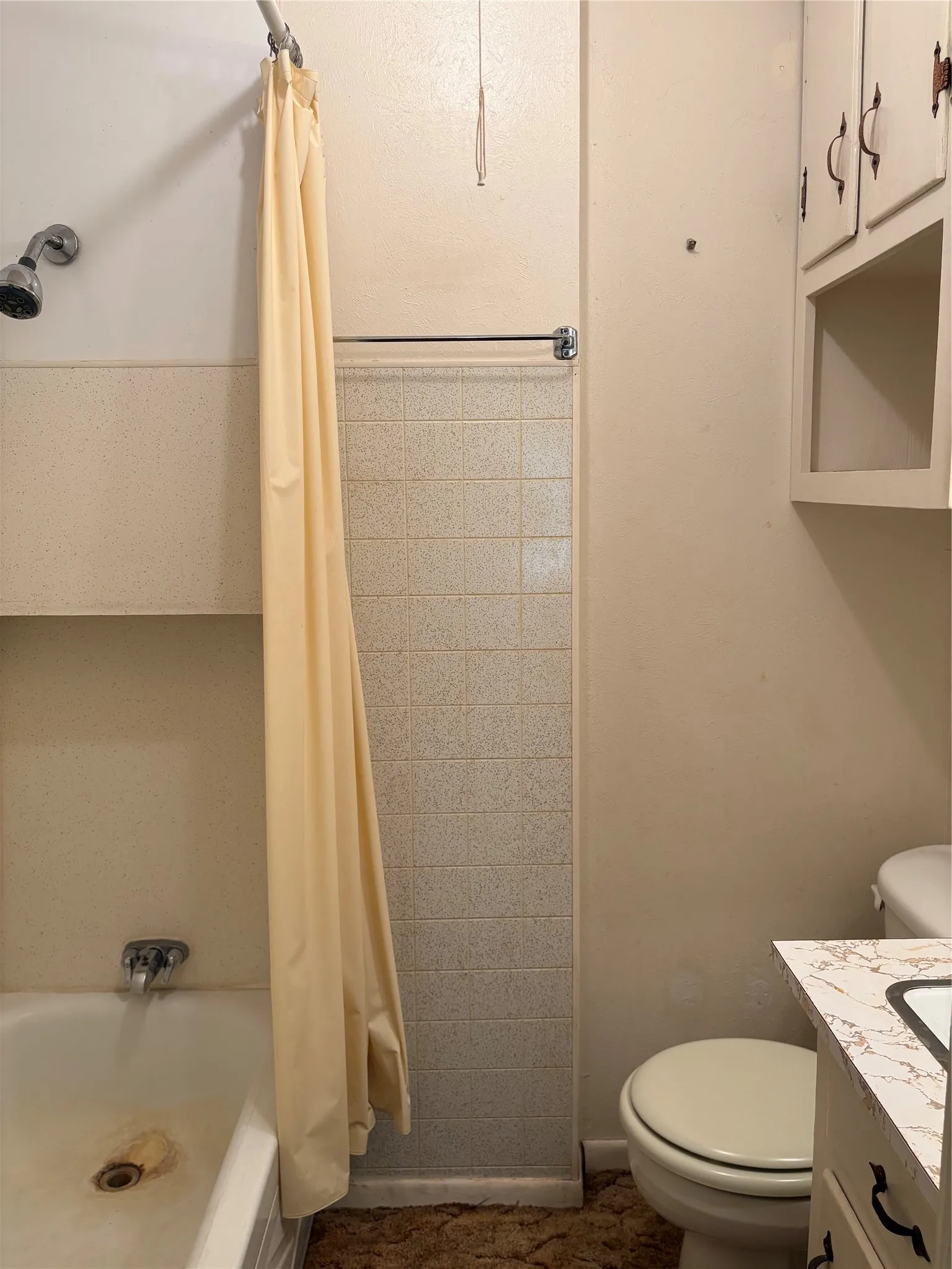 Secondary bathroom located in secondary bedroom White bathtub with chrome fixtures, tiled shower surround, and a chrome towel bar.