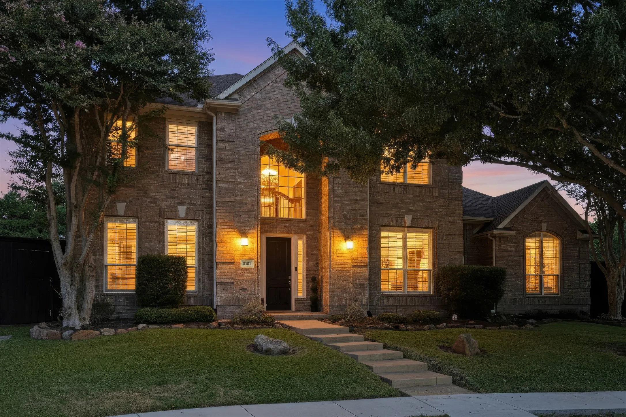 Brick exterior with a gabled roofline, multiple windows, and exterior sconce lighting