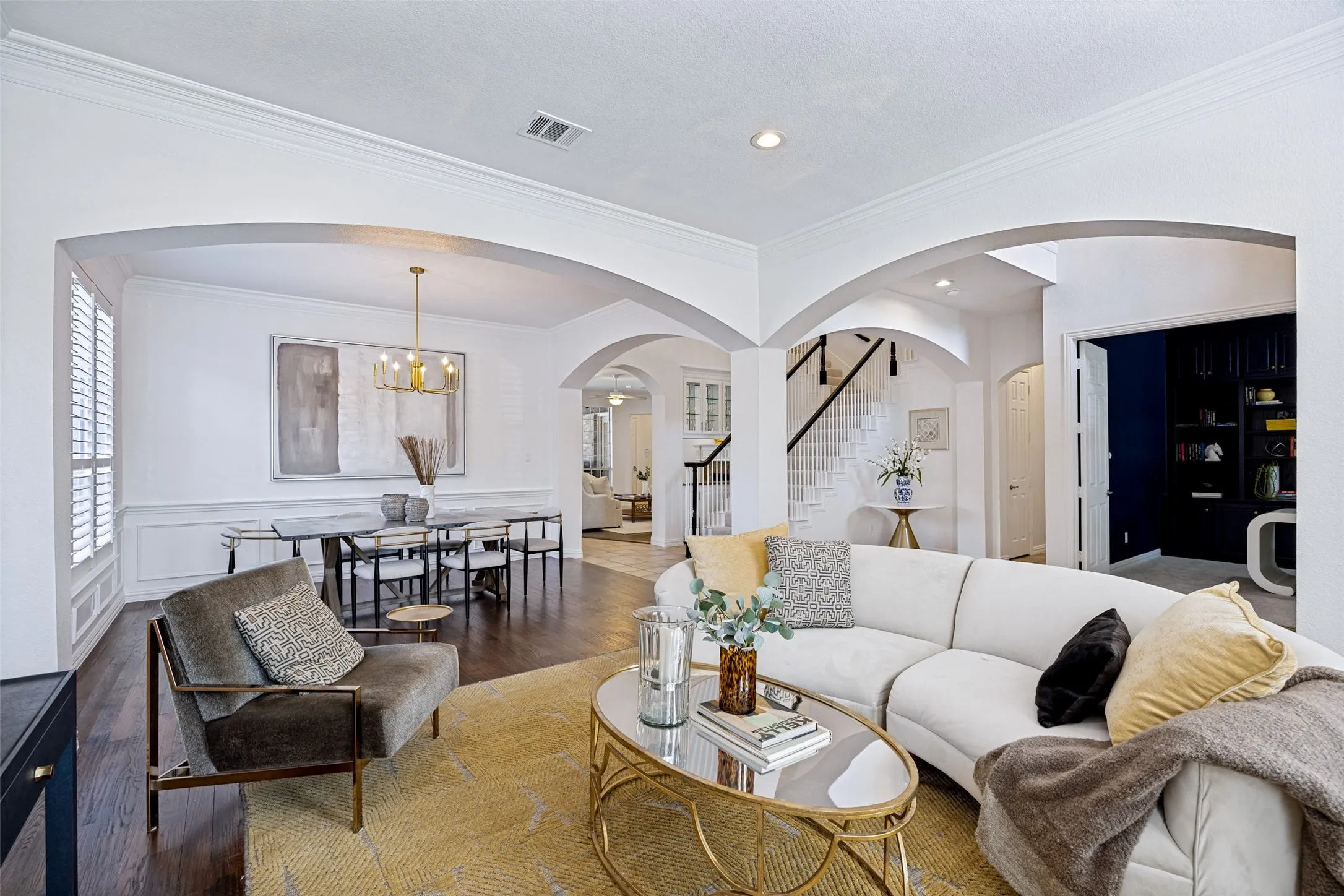 Hardwood flooring, arched doorways, crown molding, built-in shelving, and plantation shutters