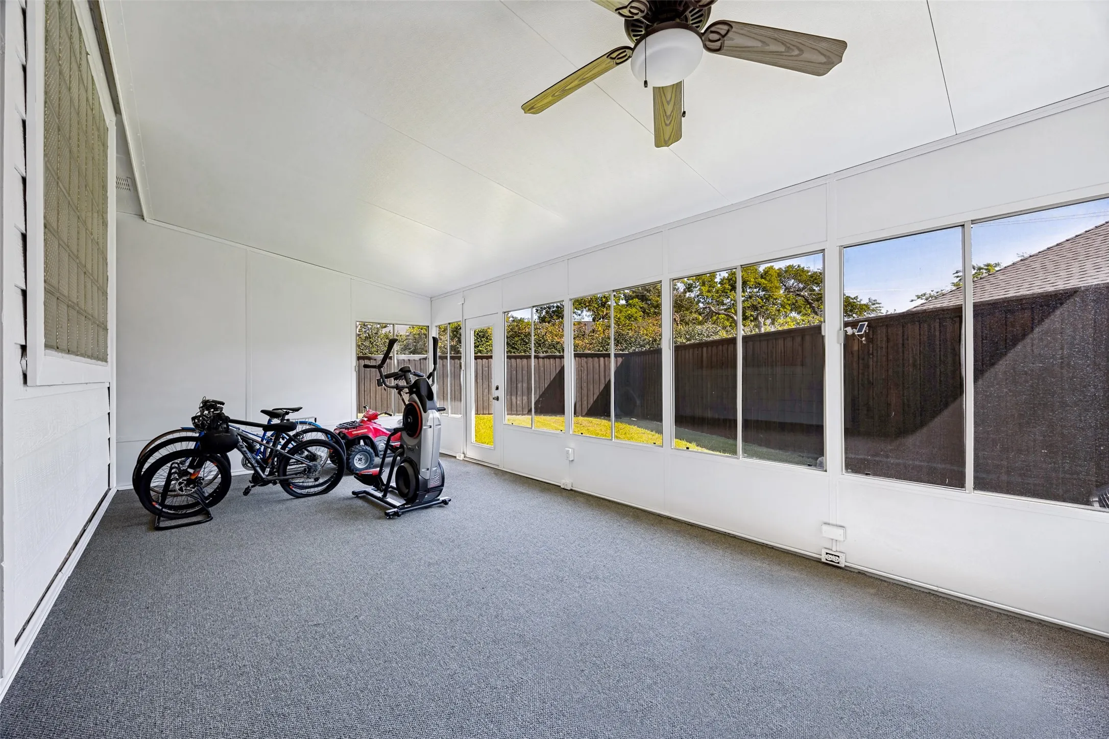 Enclosed patio with full-height windows, a ceiling fan, and light gray carpeting and heated & cooled