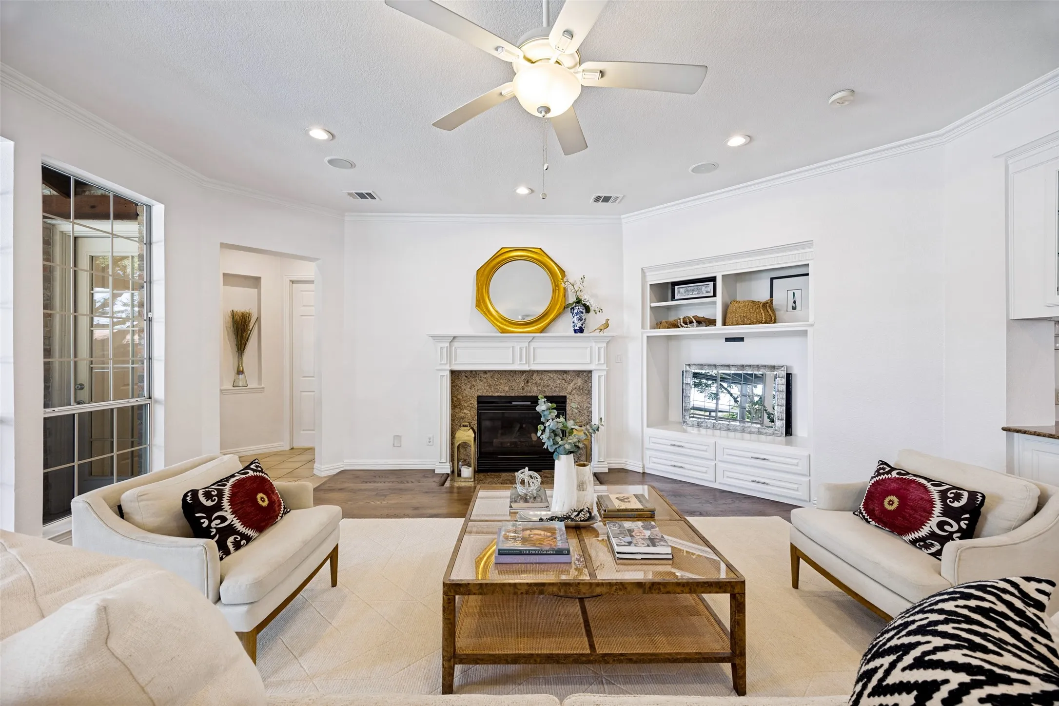 Recessed lighting, crown molding, wood-finish flooring, fireplace with stone surround, and built-in media cabinetry