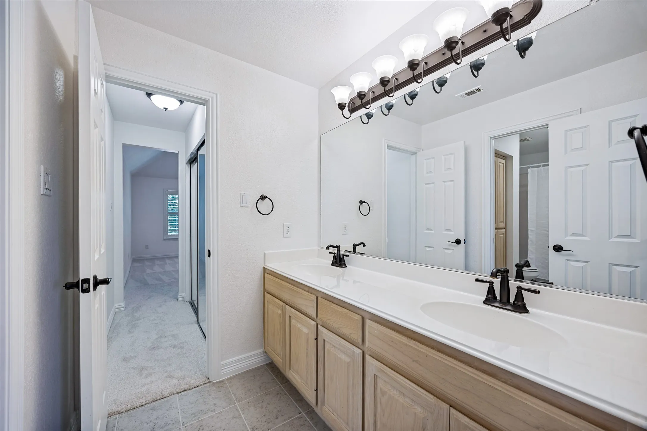 Dual vanity with undermount sinks, white countertop, and wood-finish cabinetry