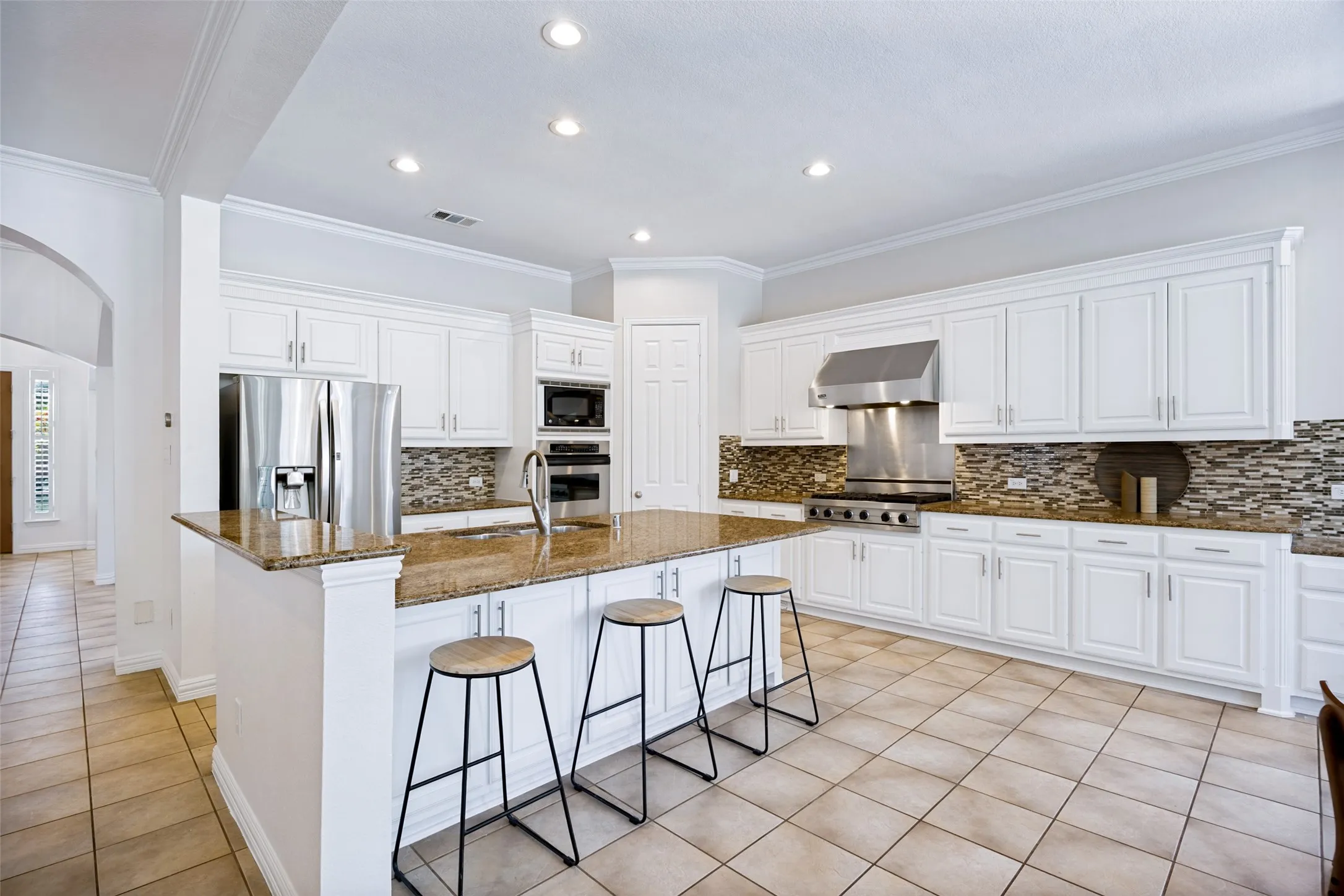 Chef's kitchen featuring white cabinetry, wood-finish countertops, and a center island with seating for three