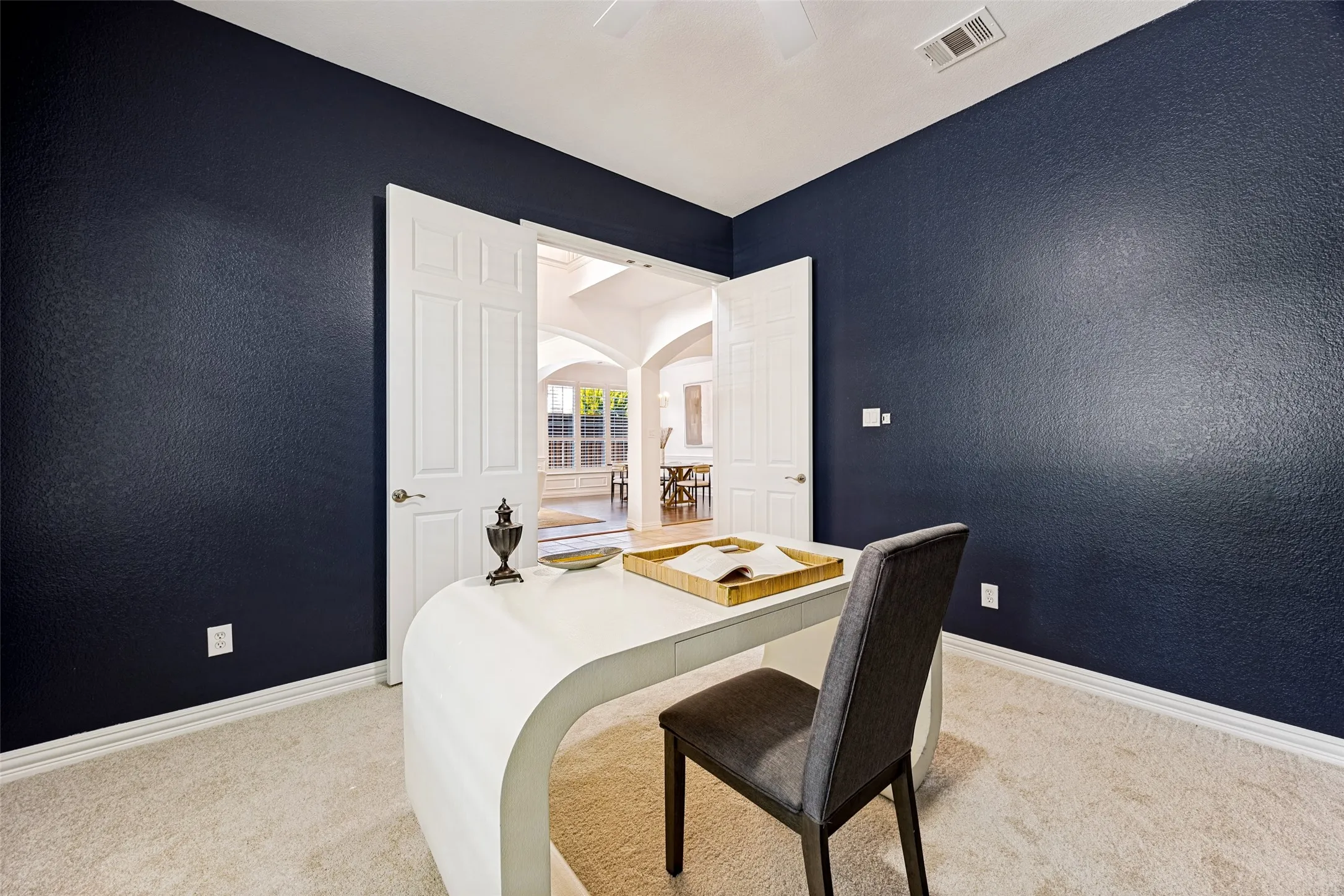 Carpeted room with dark accent walls, white trim, and a ceiling fan