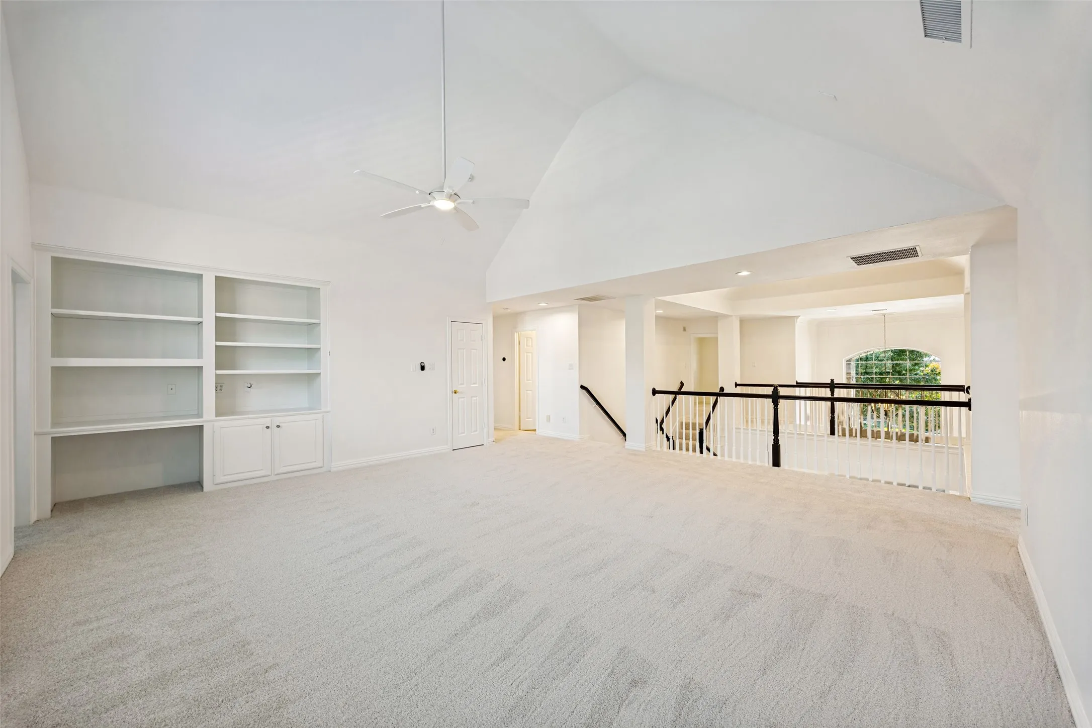 Spacious open-concept loft featuring soaring vaulted ceilings, new carpet, and abundant natural light from recessed ceiling fixtures