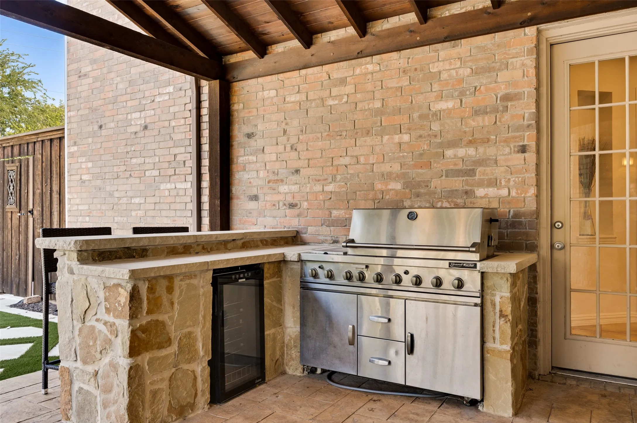 Covered patio with a stone and brick outdoor kitchen, featuring a built-in stainless steel​​‌​​​​‌​​‌‌​‌‌​​​‌‌​‌​‌​‌​​​‌​​ grill