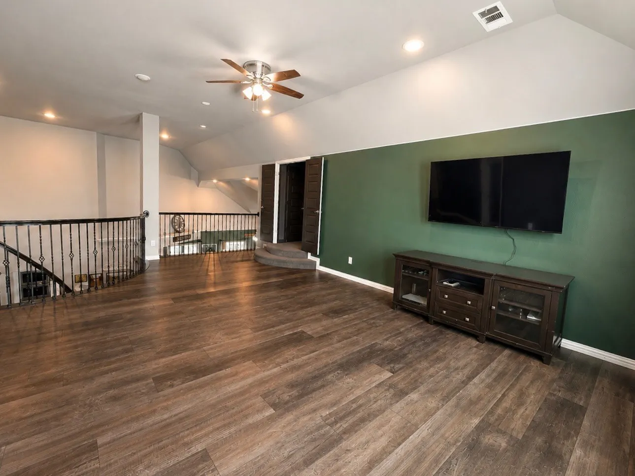 Game room located at the top of the stairs with LVP flooring, ceiling fan and lots of light.
