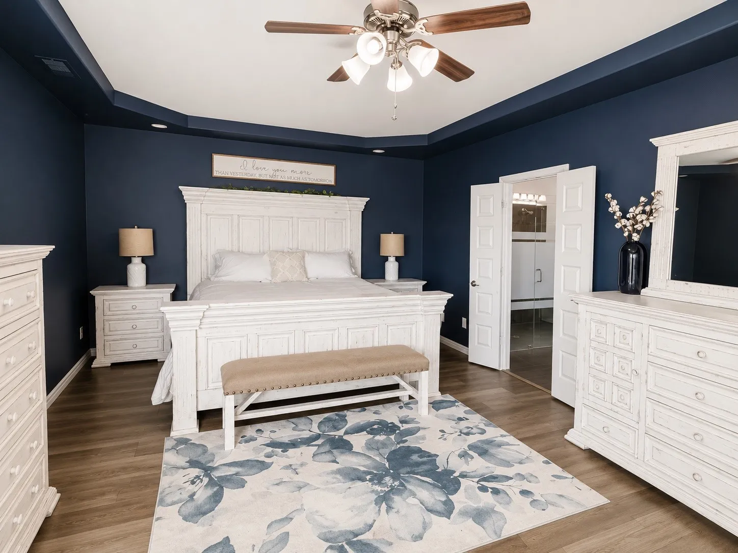 Primary bedroom with a sitting room, LVP flooring, a tray ceiling, ceiling fan and natural light.