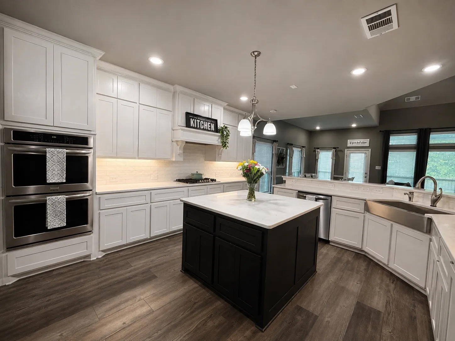 Kitchen with 4x4 island, double oven, gas stove top and stainless steel appliances. Hot water tap on kitchen sink, a walk in pantry and a butler's pantry.