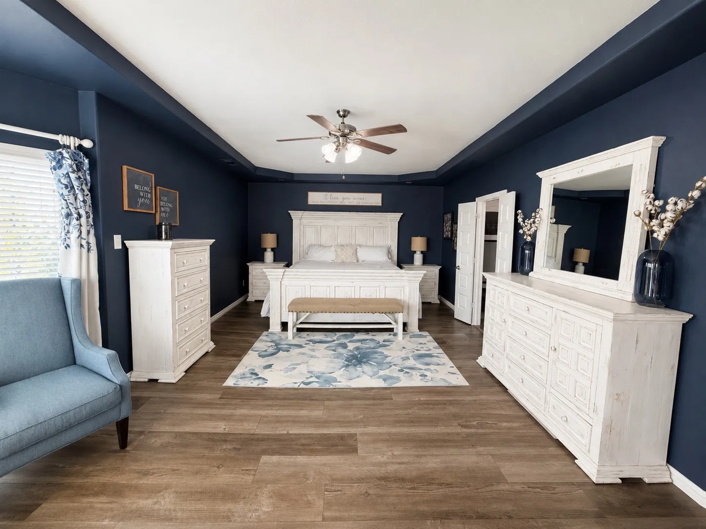 Primary bedroom with a sitting room, LVP flooring, a tray ceiling, ceiling fan and natural light.