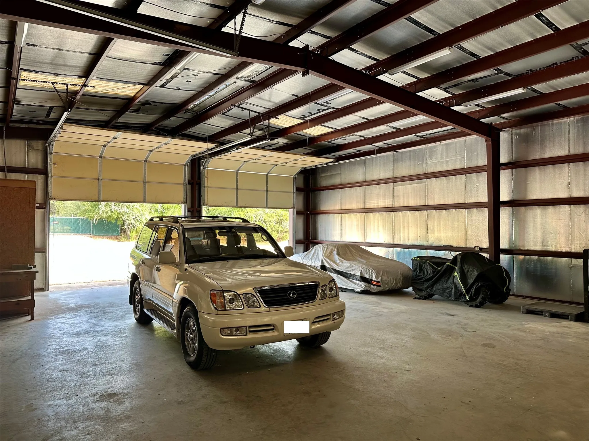 Large garage with multiple overhead doors, concrete flooring, exposed steel beam construction, and insulated walls